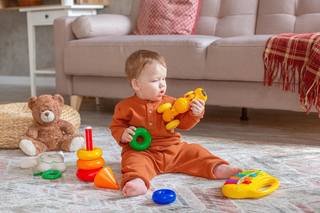 A little boy is sitting playing with toys on the floor of the house