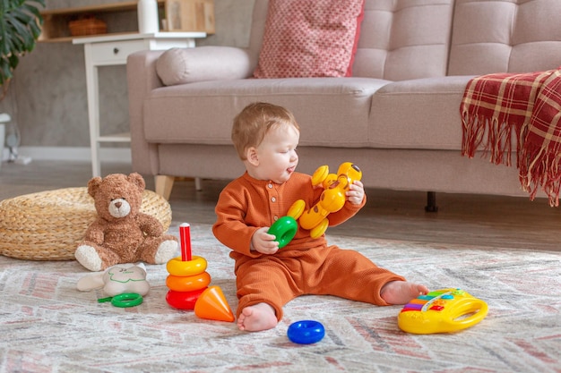 A little boy is sitting playing with toys on the floor of the house