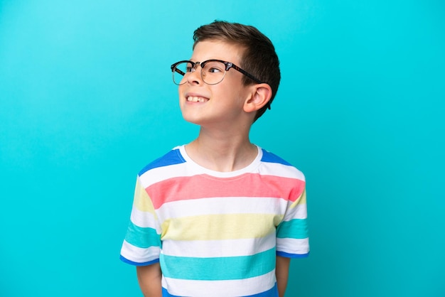 Little boy isolated on blue background With glasses with happy expression