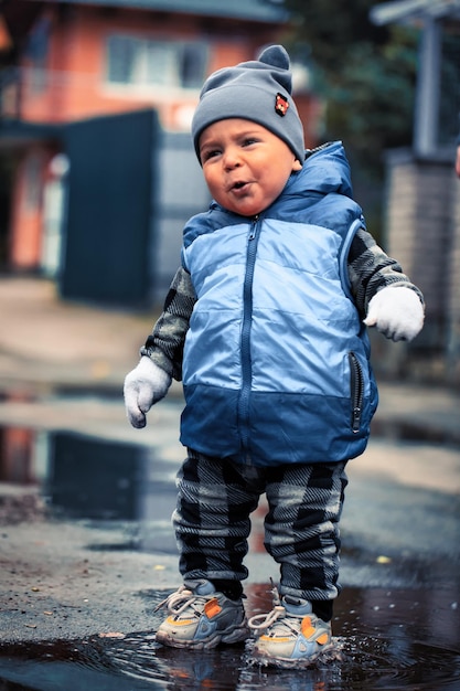 Little boy jumps in puddles Splashes of water fly in different directions