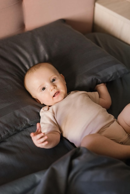 Little boy kid is lying on dark bedding on the bed