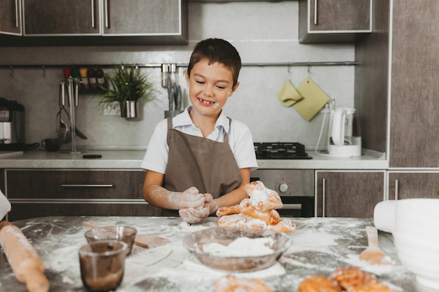 Little boy in the kitchen making dough. boy helps mom in the kitchen.