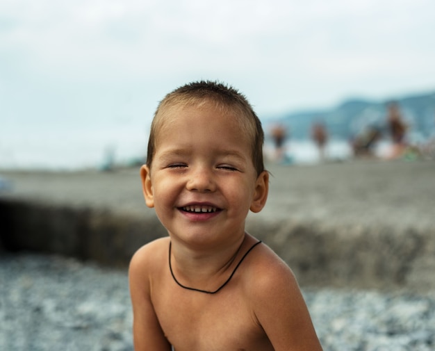 Little boy laughing with closed eyes at the beach