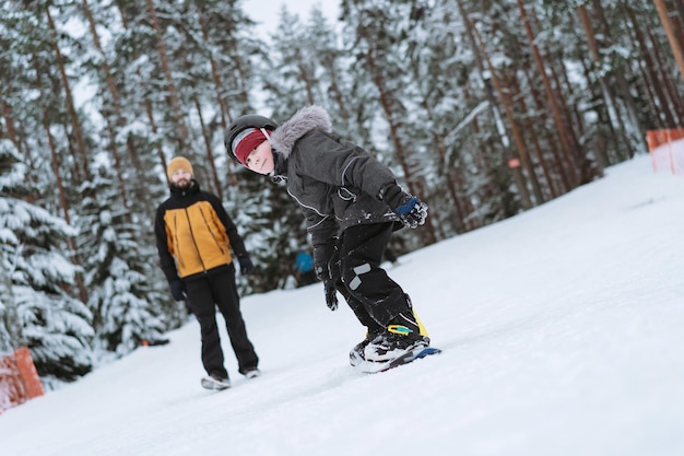 Little boy learning to ride on snowboard