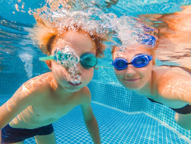 Little boy learning to swim in a swimming pool mother holding the child