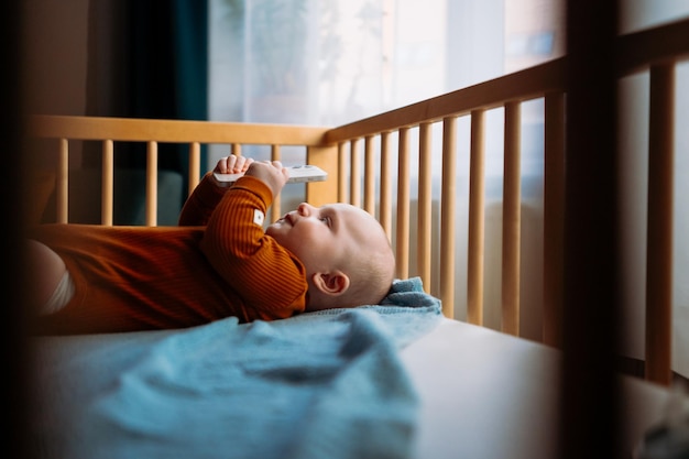 The little boy lies alone in the bed and looks at the phone