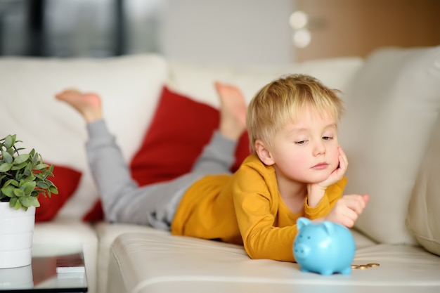 Little boy looks on moneybox and plans of what he can buy.