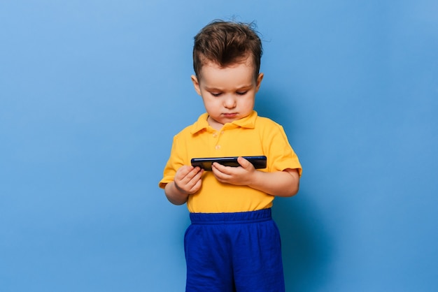 A little boy looks at the screen of a mobile phone.