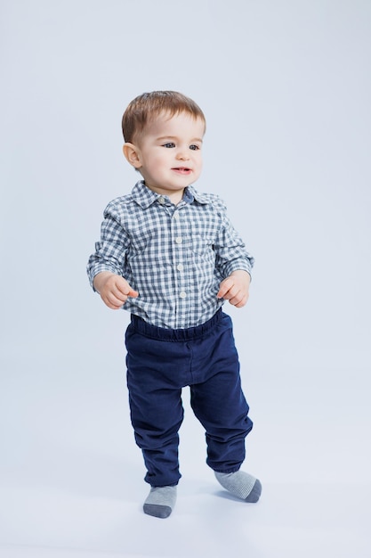 A little boy one year old on a white background in a checkered shirt A small child with a smile on his face