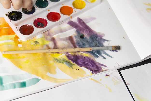 A little boy paints with watercolor paints on a table