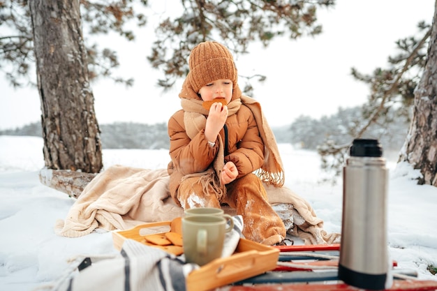 Little boy on a picnic in winter forest