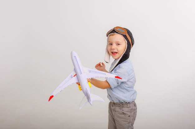 Little boy in a pilot's hat and with an airplane on a white background