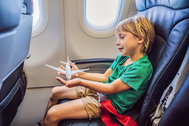 Little boy play with toy plane in the commercial jet airplane flying on vacation