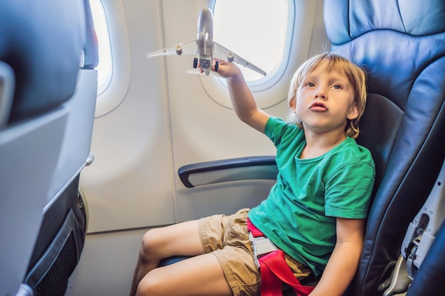 Little boy play with toy plane in the commercial jet airplane flying on vacation