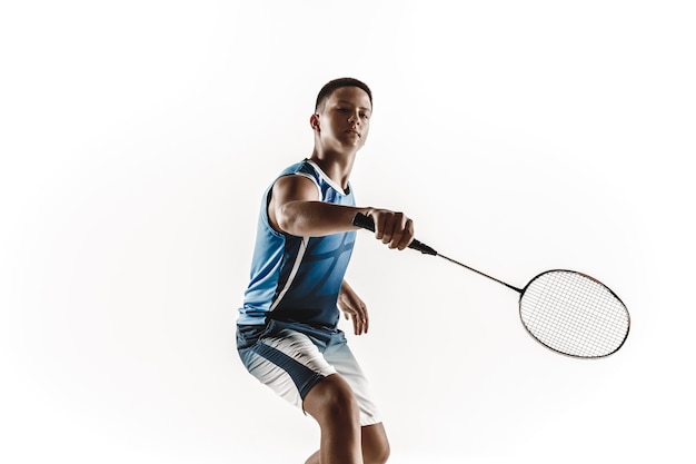 Little boy playing badminton isolated on white studio background. Young male model in sportwear and sneakers with the racket in action, motion in game. Concept of sport, movement, healthy lifestyle.