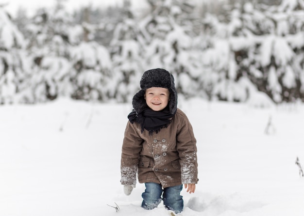 little boy playing snowballs in winter in nature