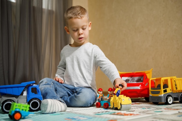 Photo little boy playing with car and truck toys