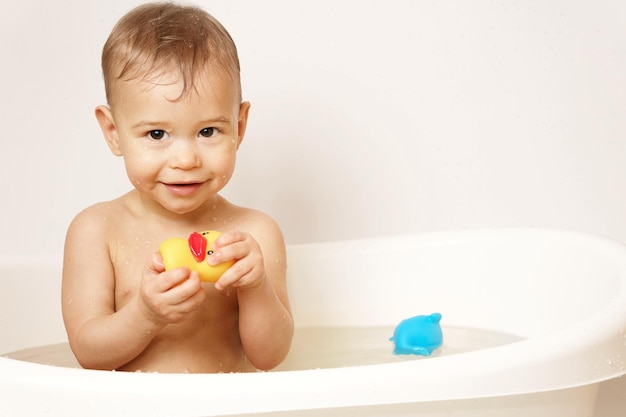 Little boy playing with rubber duck while taking a bath