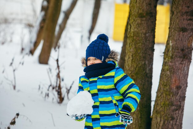 Little boy playing with snow making snowballs