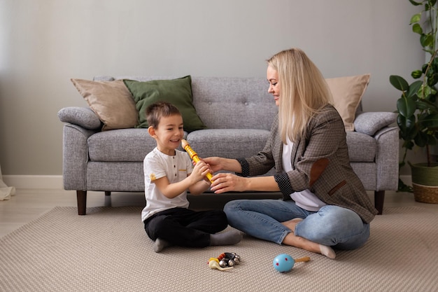 A little boy plays a pipe on the carpet in the room Mom teaches the child to play musical instruments