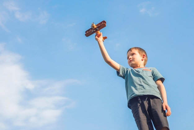 Little boy plays with toy wooden plane