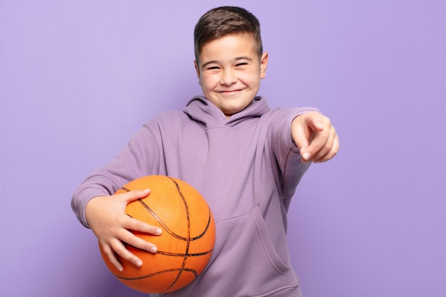 Little boy pointing or showing and holding a basketball ball