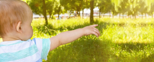 Little boy points somewhere in park banner