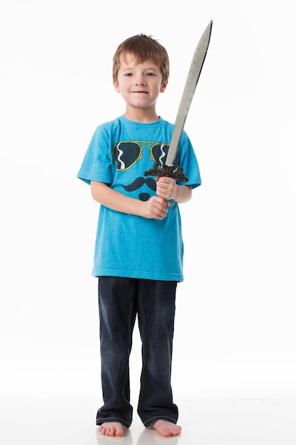 A little boy poses with a sword in a studio on a gray background