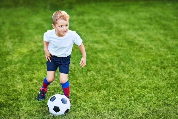 Photo little boy practising football outdoors