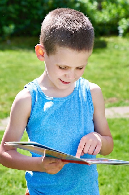 Little boy reading books outdoors