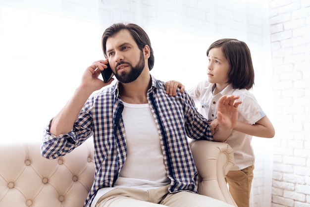 Little boy requires attention from busy father.