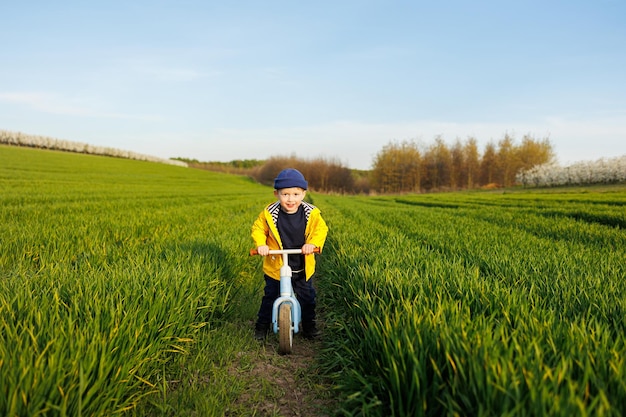 A little boy rides a blue balance bike running bike A happy child is learning to balance on an exercise bike in the garden A child is playing on the street First day on the bike