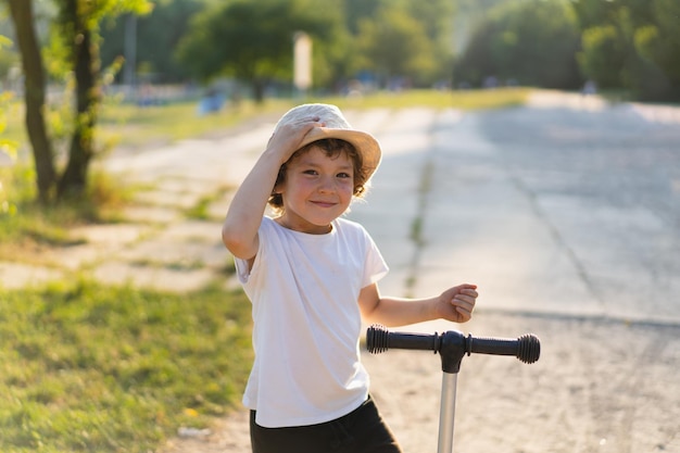 Little boy rides a scooter on sunny summer day Outdoor activity for children Active sport for preschool kid Child on kick scooter in park