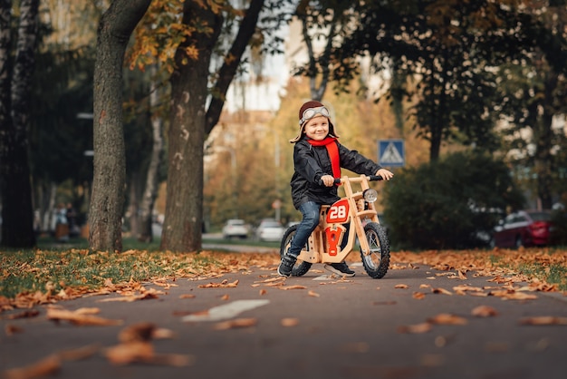 Little boy riding a balance bike in the city in autumn