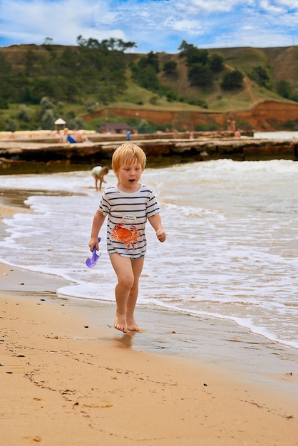 A little boy runs along the sandy beach along the seashore