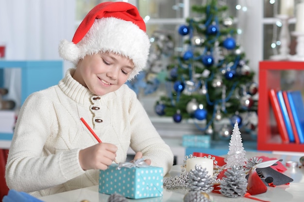 Little boy in Santa hat writing letter