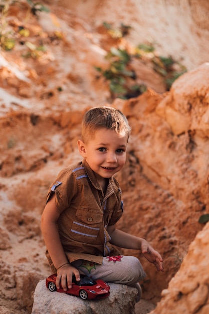 A little boy sat down on a rock among the sand