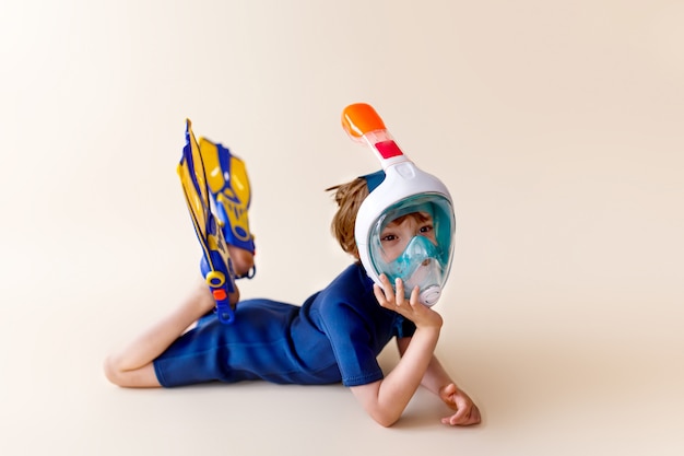 Photo little boy in scuba mask and snorkel on sand background.