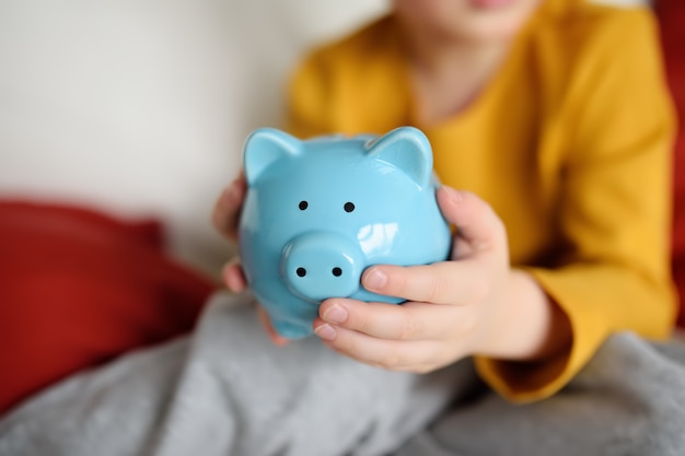 Little boy shaking a piggy moneybox and dreams of what he can buy.