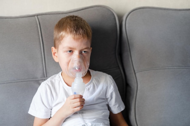 A little boy sits with an inhalation mask during cough and bronchitis