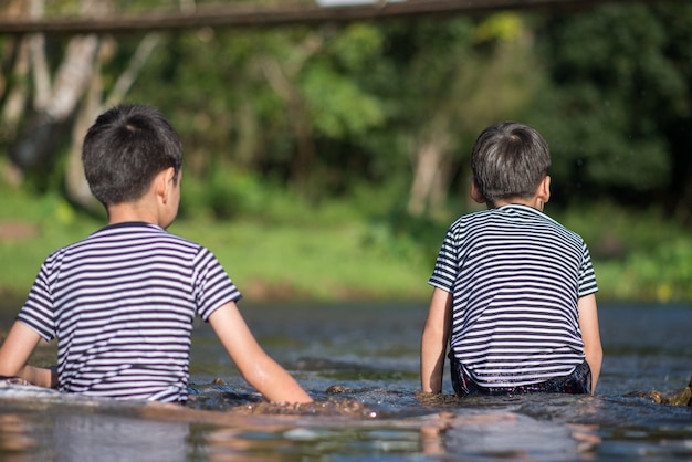 Little boy sitting together at the river canal