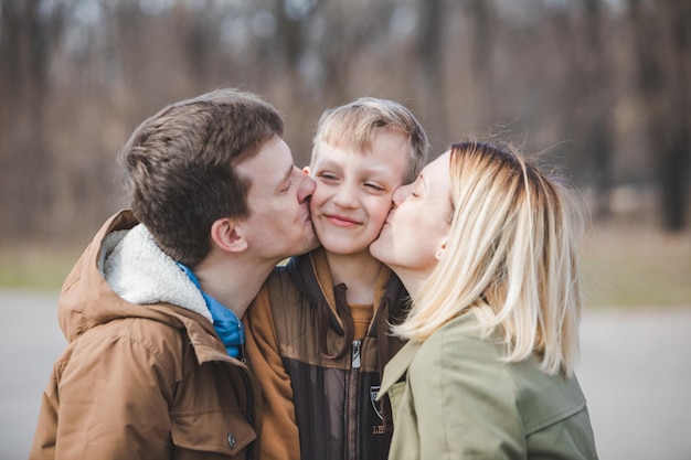 Little boy son in the middle parent kissing in both cheeks