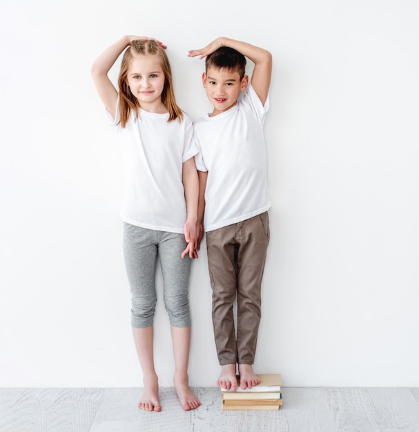 Little boy standing on books near sister