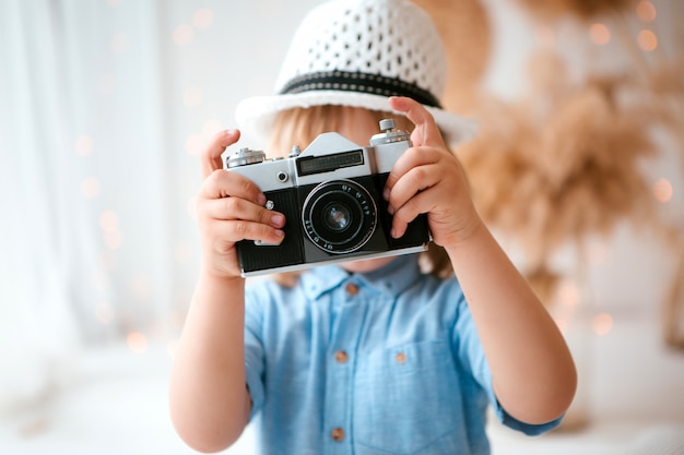 little boy in a summer hat holding a camera