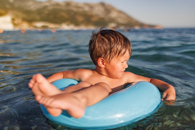 A little boy swims with an inflatable ring in the sea