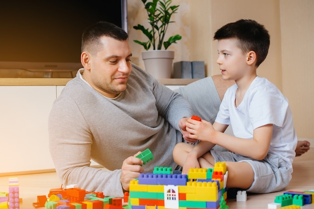 A little boy together with his father is played by a constructor and builds a house. Construction of a family home.