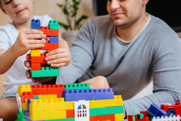 A little boy together with his father is played by a constructor and builds a house. Construction of a family home.