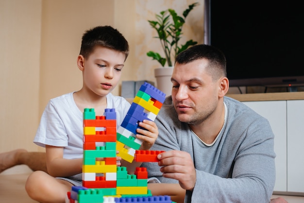 A little boy together with his father is played by a constructor and builds a house