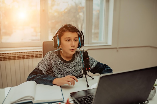 Little boy using laptop and headphones studying math during his online lesson at home social distance during quarantine selfisolation takes notes EEducation Distance Home Education