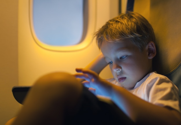 Little boy using tablet computer during flight